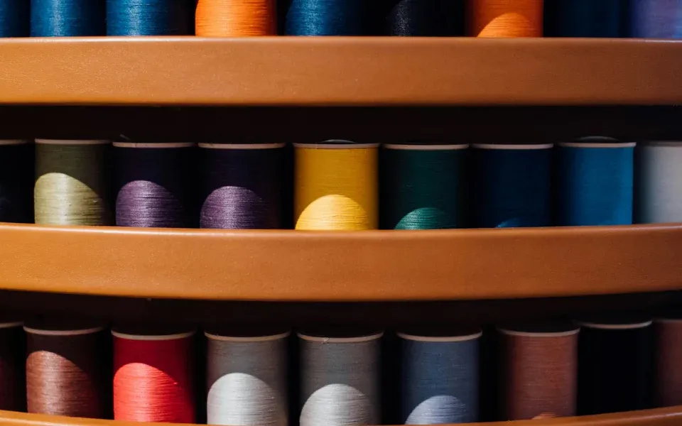 Rafturi cu fire de cusut — producție confecții, salopete și uniforme, atelier textile România