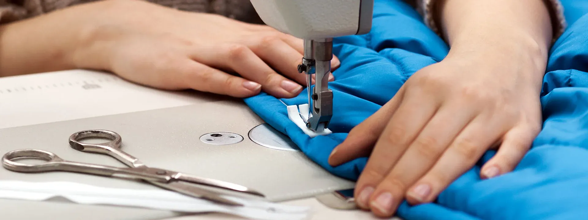 Mâini de croitoreasă la mașina de cusut — producție textile promoționale personalizate România